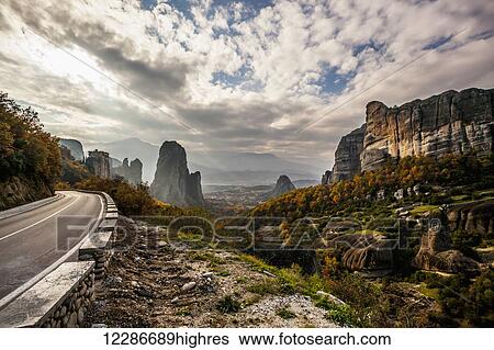 Landscape of rugged cliffs, road, autumn foliage and Monastery Rousanou in the distance; Meteora, Greece View Large Photo Image Stock Photograph - Landscape of rugged cliffs, road, autumn foliage and Monastery Rousanou in the distance; Meteora, Greece. Fotosearch
