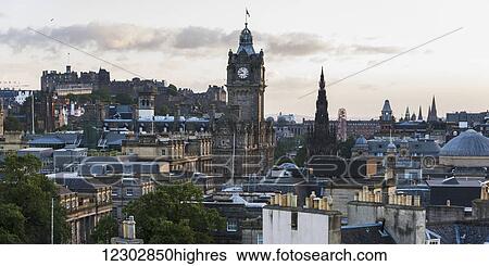 Stock Photograph - Large clock tower above a cityscape at sunrise; Edinburgh, Scotland. Fotosearch