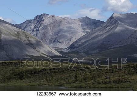Late afternoon light shining on the mountains along the Wind River in the Peel Watershed; Yukon, Canada View Large Photo Image Stock Photo - Late afternoon light shining on the mountains along the Wind River in the Peel Watershed; Yukon, Canada. Fotosearch