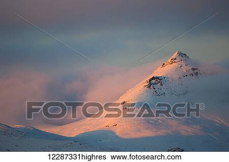 Stock Photograph - Light from the sunset illuminates the mountains along the Dempster Highway, northern Yukon; Yukon, Canada. Fotosearch