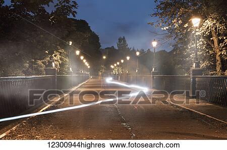 Light trail glowing in a path lit by lamp posts at dusk; Newcastle, Tyne and Wear, England View Large Photo Image Stock Photograph - Light trail glowing in a path lit by lamp posts at dusk; Newcastle, Tyne and Wear, England. Fotosearch