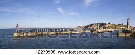 Stock Photo - Lighthouse and breakwater wall in the harbour; Whitby, North Yorkshire, England. Fotosearch
