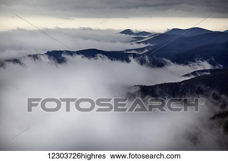Stock Photograph - Looking down on storm clouds moving up western North Carolina mountain valleys with the mountain tops and high ridges visible; North Carolina, United States of America. Fotosearch