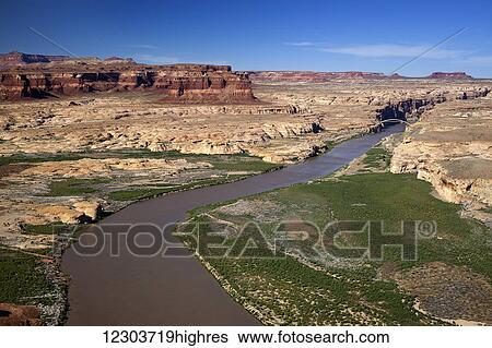 Stock Photograph - Low altitude aerial view of the Colorado River winding through canyon country of southern Utah, a bridge spanning the river in the background with red rock canyon walls and blue skies; Utah, United States of America. Fotosearch
