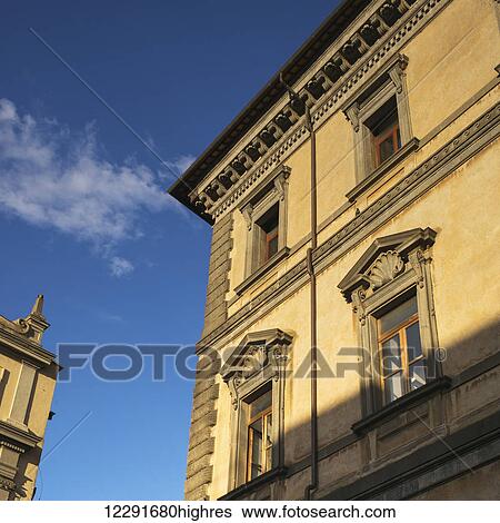 Low angle view of the facade and roofline of a yellow building and blue sky; Orvieto, Umbria, Italy View Large Photo Image Stock Photograph - Low angle view of the facade and roofline of a yellow building and blue sky; Orvieto, Umbria, Italy. Fotosearch