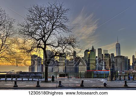 Stock Photograph - Lower Manhattan at sunset, Fruit Street sitting area; Brooklyn, New York, United States of America. Fotosearch