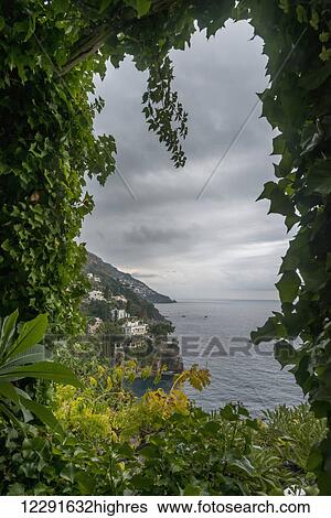 Stock Photograph - Lush foliage framing the view of the Amalfi coastline; Positano, Campania, Italy. Fotosearch