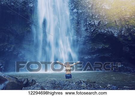 Man enjoying pool at the base of large waterfall in Hawaii View Large Photo Image Stock Photograph - Man enjoying pool at the base of large waterfall in Hawaii. Fotosearch