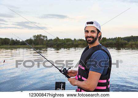 Stock Photograph - Man fishing from a boat in Lake Wabamun; Alberta, Canada. Fotosearch