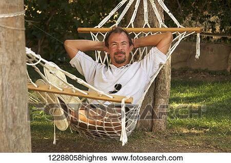 Stock Photograph - Man laying in a hammock tied to trees; Turkey. Fotosearch