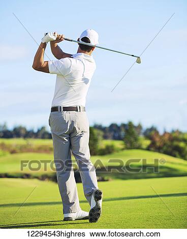 Stock Photograph - Man Playing Golf on Beautiful Sunny Green Golf Course. Hitting Golf Ball down the Fairway.. Fotosearch