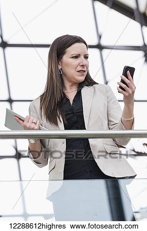 Mature business woman shocked at message received on her smart phone; Edmonton, Alberta, Canada View Large Photo Image Stock Photograph - Mature business woman shocked at message received on her smart phone; Edmonton, Alberta, Canada. Fotosearch