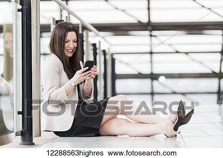 Mature business woman sitting down during a break and texting on her smart phone; Edmonton, Alberta, Canada View Large Photo Image Stock Photograph - Mature business woman sitting down during a break and texting on her smart phone; Edmonton, Alberta, Canada. Fotosearch