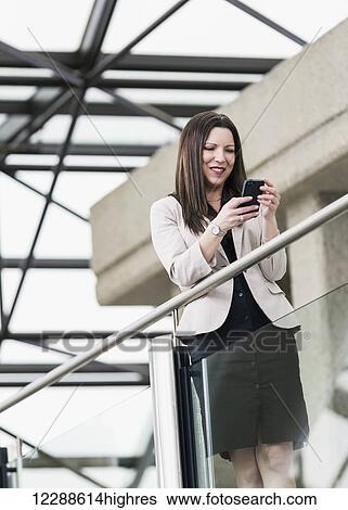 Mature business woman taking a break and texting on her smart phone; Edmonton, Alberta, Canada View Large Photo Image Stock Photograph - Mature business woman taking a break and texting on her smart phone; Edmonton, Alberta, Canada. Fotosearch