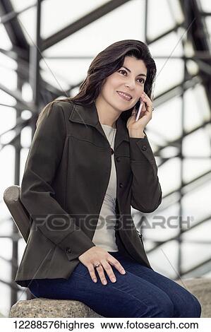 Mature business woman talking on her cell phone while taking a break in the atrium of an office building; Edmonton, Alberta, Canada View Large Photo Image Stock Photograph - Mature business woman talking on her cell phone while taking a break in the atrium of an office building; Edmonton, Alberta, Canada. Fotosearch