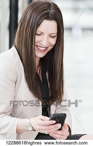 Mature business woman texting during a break from her work day; Edmonton, Alberta, Canada View Large Photo Image Stock Photograph - Mature business woman texting during a break from her work day; Edmonton, Alberta, Canada. Fotosearch