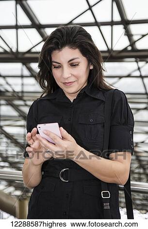 Stock Photograph - Mature business woman texting while taking a break during a business day; Edmonton, Alberta, Canada. Fotosearch