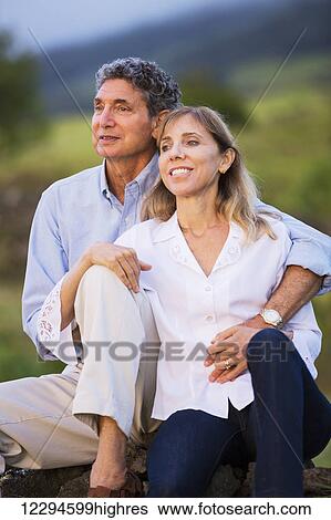 Stock Photograph - Mature middle age couple in love watching the sunset. Fotosearch