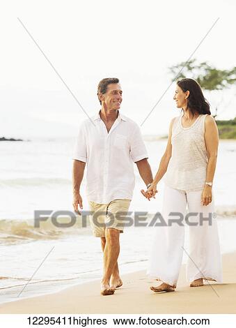 Mature Retired Couple Enjoying Sunset Walk on the Beach View Large Photo Image Stock Photograph - Mature Retired Couple Enjoying Sunset Walk on the Beach. Fotosearch
