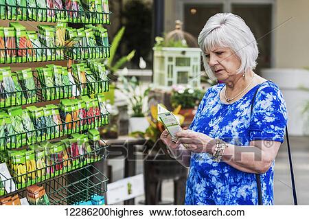 Mature woman shopping for garden seeds in a garden centre in a shopping complex; St. Albert, Alberta, Canada View Large Photo Image Stock Photograph - Mature woman shopping for garden seeds in a garden centre in a shopping complex; St. Albert, Alberta, Canada. Fotosearch