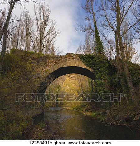 Stock Photograph - Medieval bridge called Puente de Santa Maria on the River Cidacos, in the village of Yanguas; Soria, Spain. Fotosearch