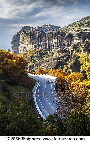 Stock Photograph - Monasteries perched on cliffs and a winding road in autumn foliage; Meteora, Greece. Fotosearch