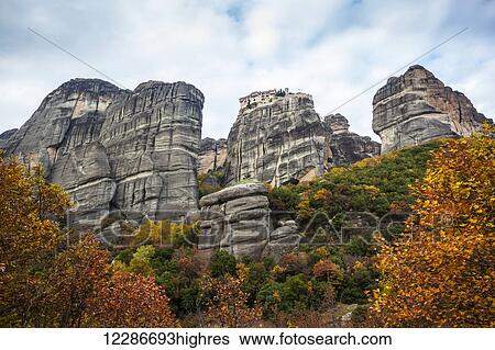 Stock Photograph - Monastery perched on a cliff with autumn foliage; Meteora, Greece. Fotosearch