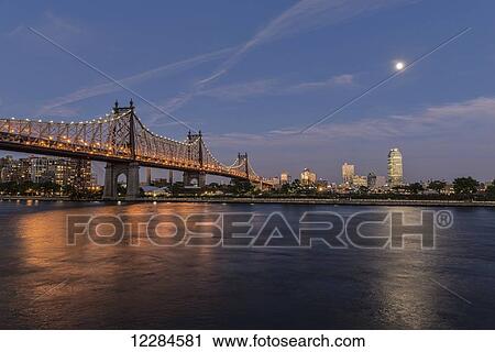 Stock Image - Moonrise over Queensboro (59th Street) Bridge and the Citibank Building; Queens, New York, United States of America. Fotosearch