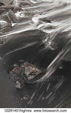 Stock Photograph - Morning surf washes through the black sands at Punaluu Beach; Island of Hawaii, Hawaii, United States of America. Fotosearch