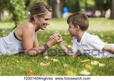 Stock Photograph - Mother arm wrestling with her son in a park during a family outing; Edmonton, Alberta, Canada. Fotosearch