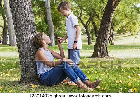 Mother getting a flower from her son while spending quality time at a park during a family outing; Edmonton, Alberta, Canada View Large Photo Image Stock Photograph - Mother getting a flower from her son while spending quality time at a park during a family outing; Edmonton, Alberta, Canada. Fotosearch