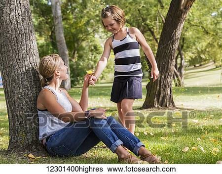 Mother getting a flower from her daughter while spending quality time at a park during a family outing; Edmonton, Alberta, Canada View Large Photo Image Stock Photograph - Mother getting a flower from her daughter while spending quality time at a park during a family outing; Edmonton, Alberta, Canada. Fotosearch