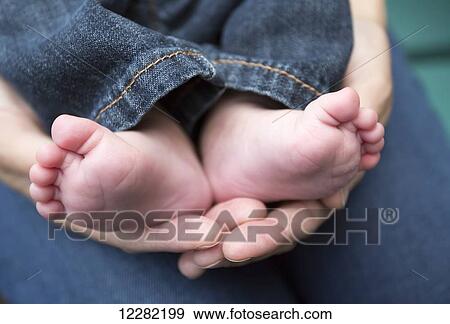 Stock Photo - Mother holding infant boy's bare feet; Chilliwack, British Columbia, Canada. Fotosearch
