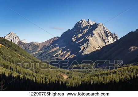 Mountain with jagged peaks and forested valley and blue sky, Kananaskis Provincial Park; Alberta, Canada View Large Photo Image Stock Photograph - Mountain with jagged peaks and forested valley and blue sky, Kananaskis Provincial Park; Alberta, Canada. Fotosearch