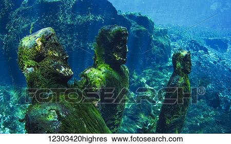 Stock Photograph - Movie props statues covered in green moss in freshwater spring. Fotosearch