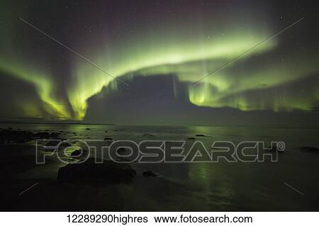 Stock Photograph - Northern lights dancing over the Langanes Peninsula and the Atlantic Ocean; Iceland. Fotosearch
