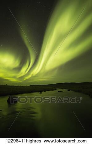 Stock Photograph - Northern Lights, or Aurora Borealis, glowing over a stream; Iceland. Fotosearch