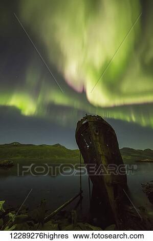 Stock Photograph - Northern lights over top of the town known as Djupavik along the Strandir Coast, here they are dancing above the old herring factory and shipwreck; Djupavik, Iceland. Fotosearch