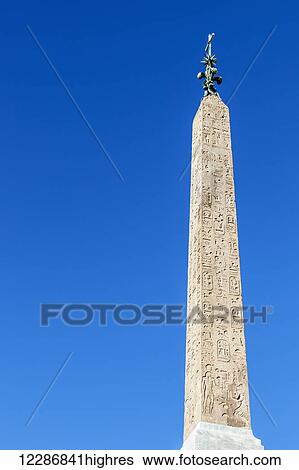 Stock Photograph - Obelisk with statue on top and etchings on facade; Rome, Italy. Fotosearch