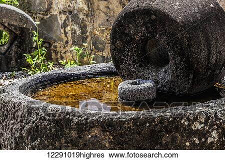 Stock Photograph - Old millstone from the time of Christ that was uncovered in Capernaum on the north shore of the Sea of Galilee, this grinding wheel which could work even today; Capernaum, Israel. Fotosearch
