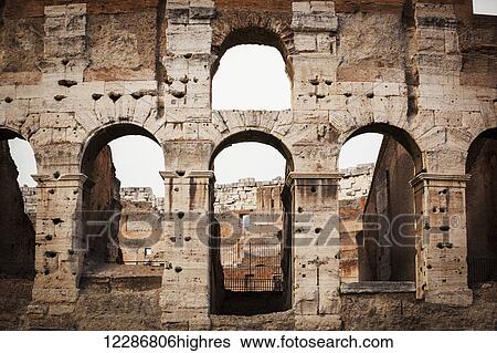 Stock Photograph - Old stone wall of Colosseum with arches; Rome, Italy. Fotosearch