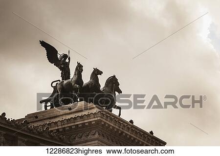 Stock Photograph - On either side of the roof-top viewing area was the goddess Victoria riding on quadrigas; Rome, Italy. Fotosearch