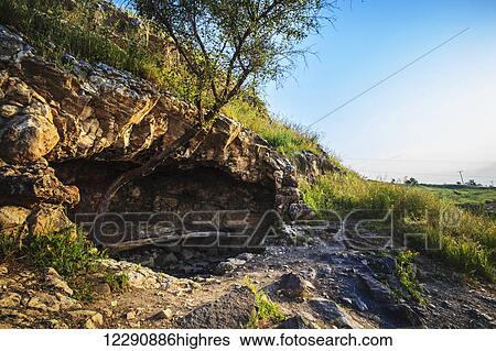 Stock Photograph - On the north shore just below the Mount of Beatitudes and above were Jesus feed the 5000 is a little cave where tradition tells us Jesus would get away by Himself; Galilee, Israel. Fotosearch