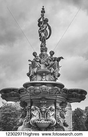 Stock Photograph - Ornate fountain (Ross fountain) with sculptures of women against a cloudy sky, Princes Street Gardens; Edinburgh, Scotland. Fotosearch