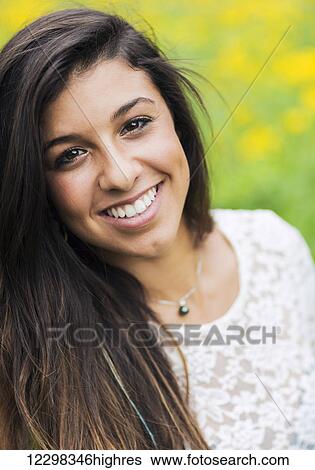 Stock Photograph - Outdoor portrait of a beautiful young brunette woman smiling happy. Fotosearch