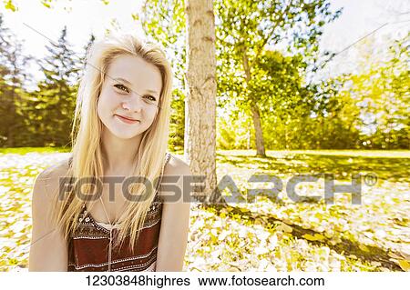 Stock Photograph - Outdoor portrait of a beautiful young woman with long, blond hair in a city park in autumn; Edmonton, Alberta, Canada. Fotosearch