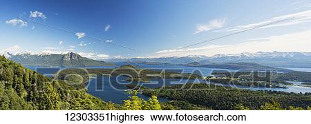 Stock Photograph - Panoramic view of a large lake in Patagonia, with snow-capped mountains and blue sky; Argentina. Fotosearch