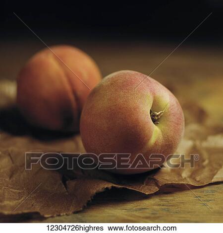 Peaches sitting on brown parchment paper on a wooden counter; Toronto, Ontario, Canada View Large Photo Image Stock Photograph - Peaches sitting on brown parchment paper on a wooden counter; Toronto, Ontario, Canada. Fotosearch