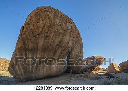 Person standing under a large boulder in Richtersveld National Park; South Africa View Large Photo Image Stock Photo - Person standing under a large boulder in Richtersveld National Park; South Africa. Fotosearch
