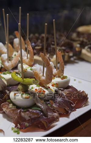 Stock Photo - Pintxos of bread, ham, prawns and egg on a on a bar counter in the old town; San Sebastian, Spain. Fotosearch